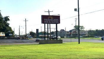 The image shows a grassy roadside with a sign for 