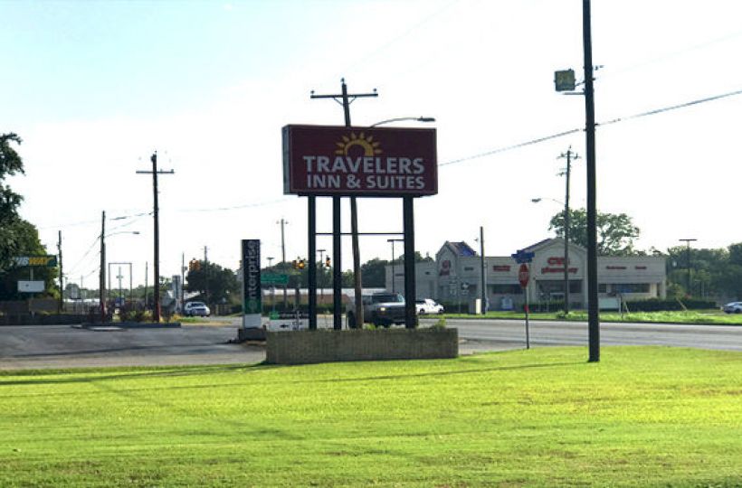 The image shows a grassy roadside with a sign for 